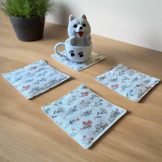 Floral coasters on a wooden surface with a small dog toy in a mug.